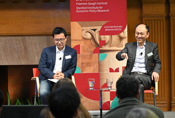 Yiqing Xu and Hongbin Li sit on a stage during a SCCEI event.