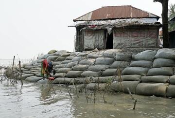A woman stands on sandbags stacked to protect against flooding in Barisal, Bangladesh.