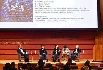 On an auditorium stage, panelists discuss the documentary 'A Chip Odyssey.'