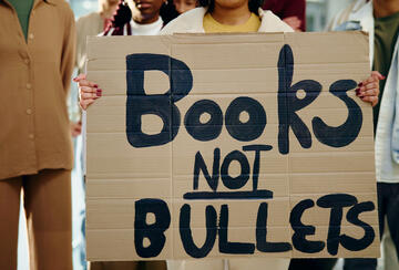 An image of students holding a protest sign that reads "Books not bullets" 