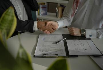 Two people shaking hands over a piece of paper