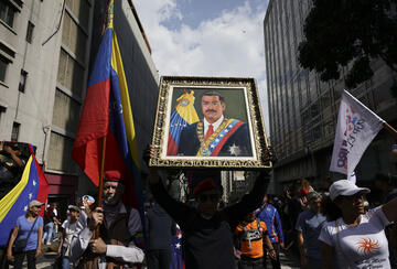man holds a portrait of nicolas maduro during a march