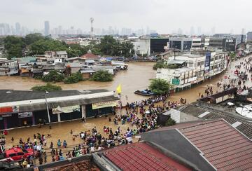 People walk through the flooded streets at Kampung Pulo on January 18, 2014 in Jakarta, Indonesia.