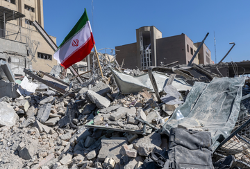 An Iranian flag is planted in the rubble of a police station, damaged in airstrikes on March 3, 2026 in Tehran, Iran.