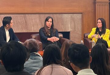 Three speakers during a panel discussion, seated on stage in the Bechtel Conference Center, Stanford University.