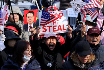 Supporters of impeached South Korean President Yoon Suk Yeol gather on April 4, 2025 in Seoul, South Korea, with a foucs on a man holding a sign reading "Stop the Steal" and an American flag.