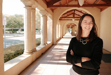 Stanford's Maria Polyakova stands amid the university's sandstone columns.