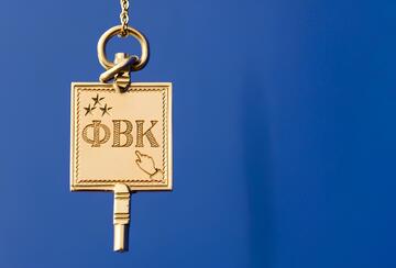 Hanging gold charm with greek letters "Phi Beta Kappa" on blue background