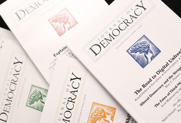 Spread of issues of the Journal of Democracy on black background