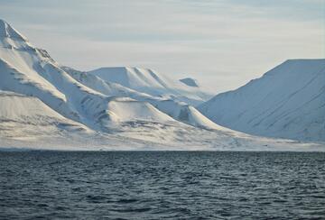 Snow-capped mountains and a seascape on the shore of the Arctic town of Longyearbyen.