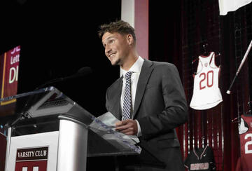 Ni White in a suit and tie giving a speech at a podium at Harvard University