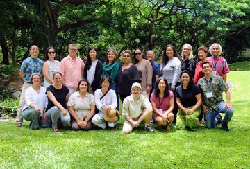 group of educators posing in front of a lush green canopy