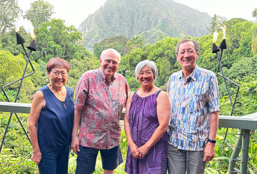 four people standing in Hawaiin shirts and dresses
