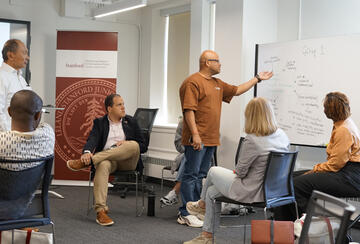 Francis Fukuyama looks on as a group of fellows works through a case study.