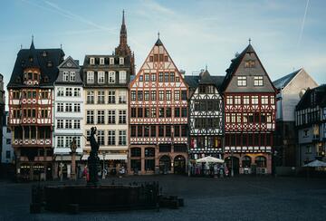 Row of half-timbered buildings on Frankfurt’s Römerberg square, with a Justitia fountain statue in the foreground.