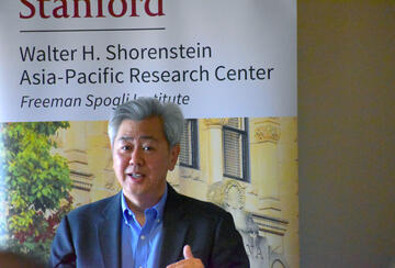 Andrew Kim speaking at a lectern during an APARC event.