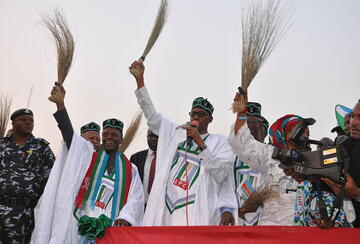 general buhari holding a broom at a campign rally