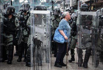 Woman shouts at police officers as they advance towards protesters in Hong Kong