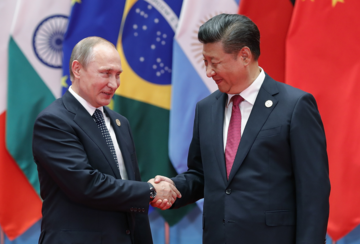 Vladamir Putin and Xi Jinping shake hands.