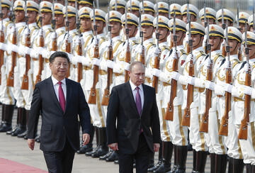 Photograph of Xi Jinping and Vladmir Putin walking in front of two lines of armed Chinese soldiers