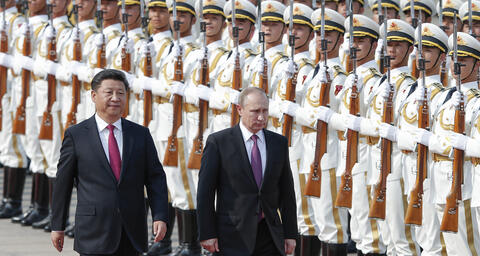 Photograph of Xi Jinping and Vladmir Putin walking in front of two lines of armed Chinese soldiers