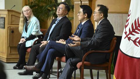 Three men and a woman seated for a panel discussion in a conference room.
