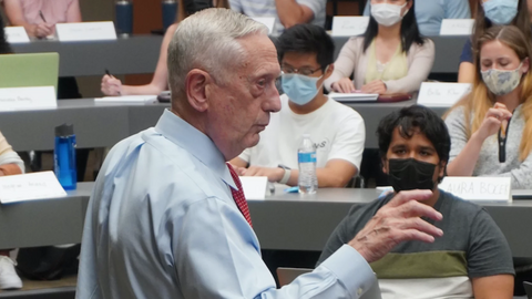 Man in blue shirt lectures before students