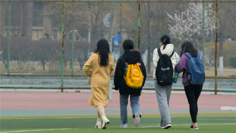 Students with backpacks walk away on a school campus.
