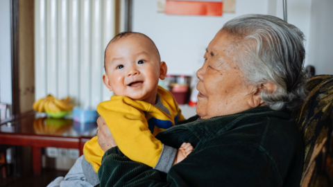 Grandma holds up smiling baby.