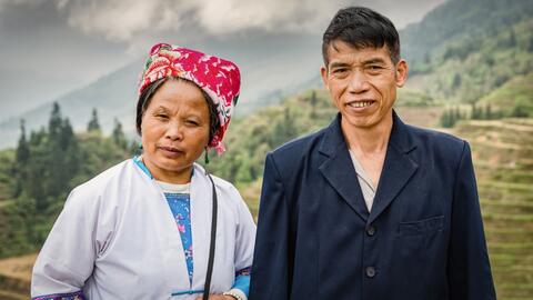 Chinese agriculture working couple standing side by side on the top of a rice terraces at Ping An Village looking to the camera.