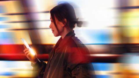 woman looking at her phone with background of city lights