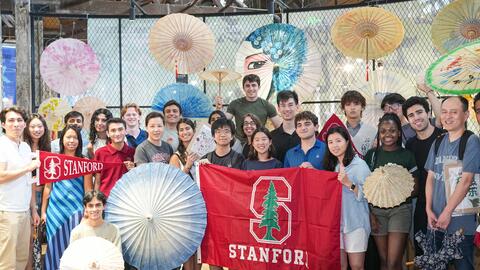 Group photo of students and staff from the summer study program with paper umbrellas.