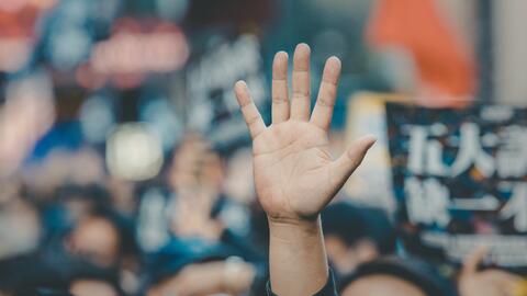 Man with long sleeve black shirt raising hand in a crowd