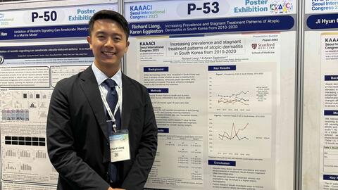 Richard Liang standing next to a poster presenting his research at a conference. 