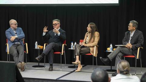 Four people during a panl discussion on stage.