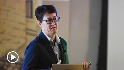 Jun Akabane delivers a presentation at a lectern. 