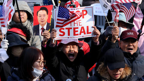 Supporters of impeached South Korean President Yoon Suk Yeol gather on April 4, 2025 in Seoul, South Korea, with a foucs on a man holding a sign reading "Stop the Steal" and an American flag.
