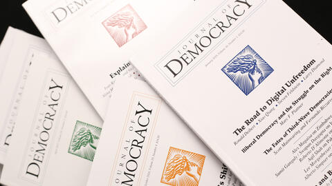 Spread of issues of the Journal of Democracy on black background