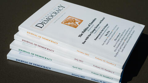 Stack of issues of the Journal of Democracy on black background