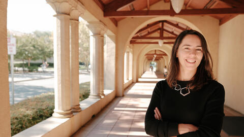 Stanford's Maria Polyakova stands amid the university's sandstone columns.