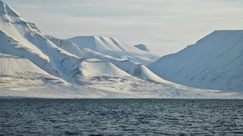 Snow-capped mountains and a seascape on the shore of the Arctic town of Longyearbyen.