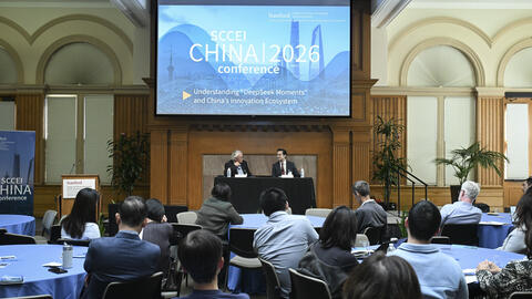 A full room of attendees seated at round tables during a conference. 