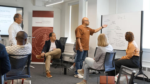 Francis Fukuyama looks on as a group of fellows works through a case study.
