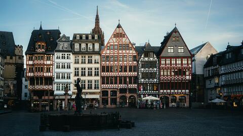 Row of half-timbered buildings on Frankfurt’s Römerberg square, with a Justitia fountain statue in the foreground.