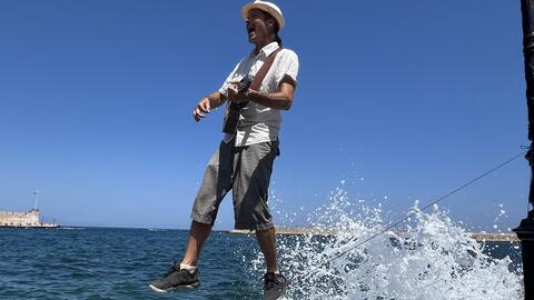 man playing the ukulele on a rope over the ocean
