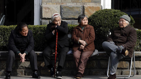 Four elderly Chinese people sitting outdoors. 