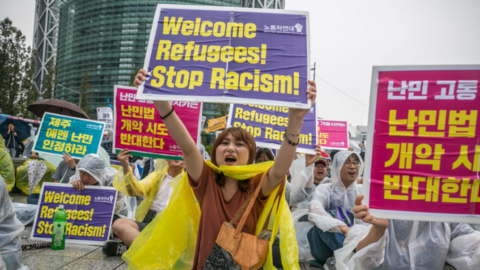 Pro-immigration demonstrators hold signs at a rally in Seoul.