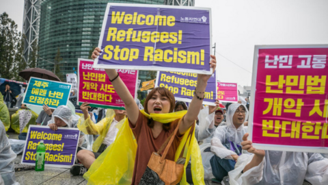 Pro-immigration demonstrators hold signs at a rally in Seoul. 