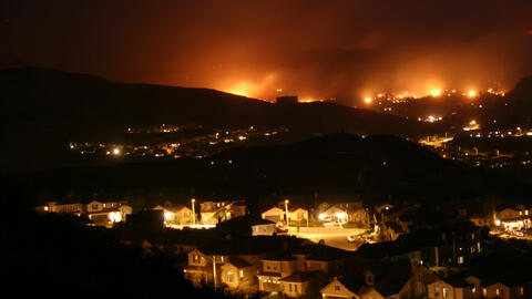 A suburban town at night with wildfires approaching in the distance