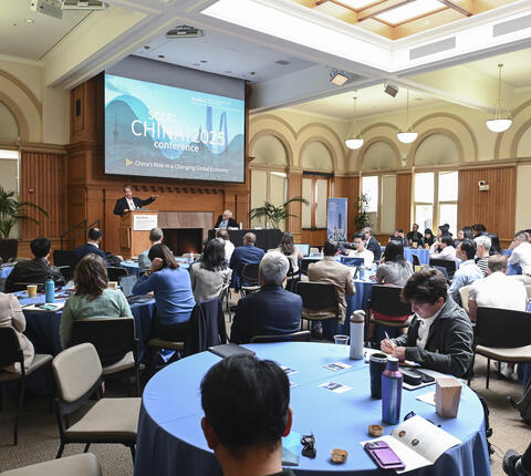 2025 SCCEI China Conference room with audience seated at rounds and Sean Stein and Scott Rozelle on stage.
